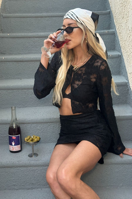 Woman in black lace outfit drinking red wine on steps