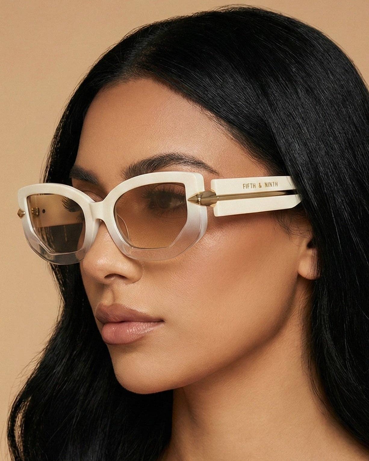 Woman wearing a pair of sunglasses with a beige frame on a beige background