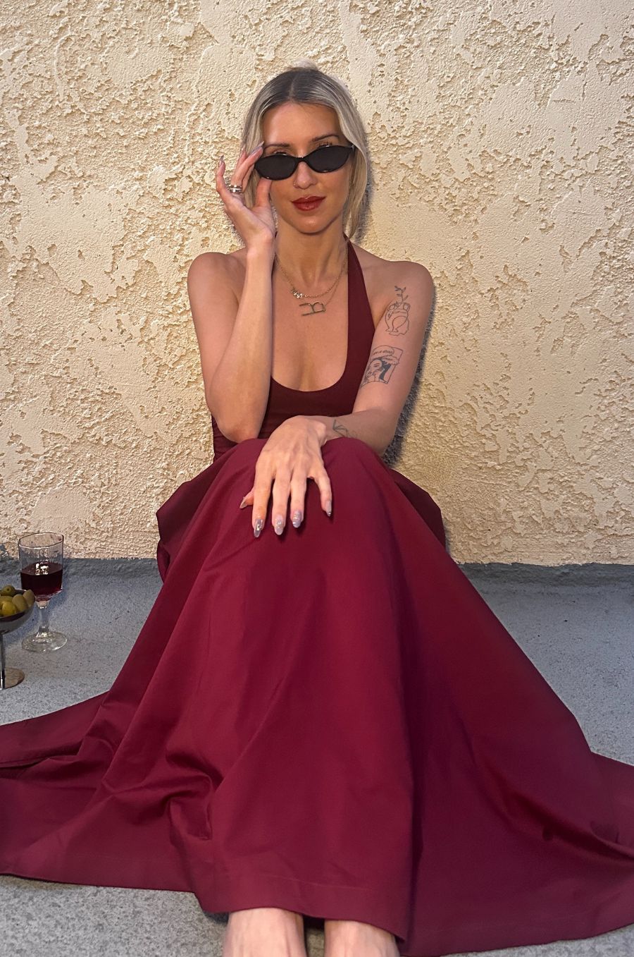 Woman in a burgundy dress sitting on a textured wall background