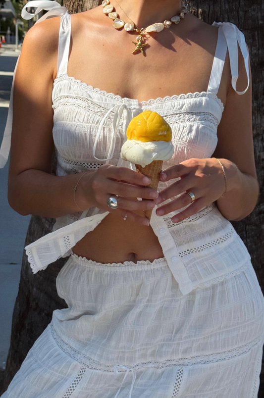 Woman in a white dress holding a yellow ice cream cone.