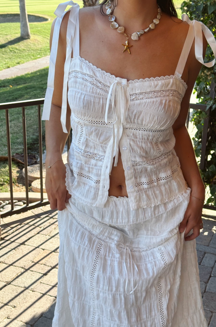 Woman wearing a white lace dress with a blurred outdoor background