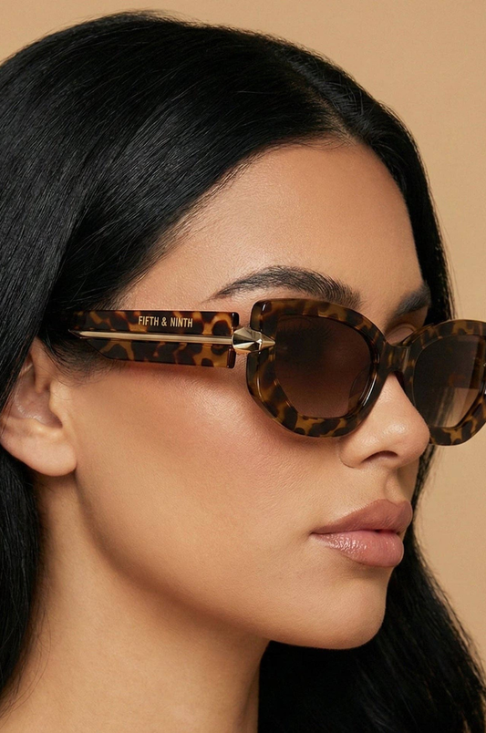 Person wearing leopard print sunglasses with a neutral background
