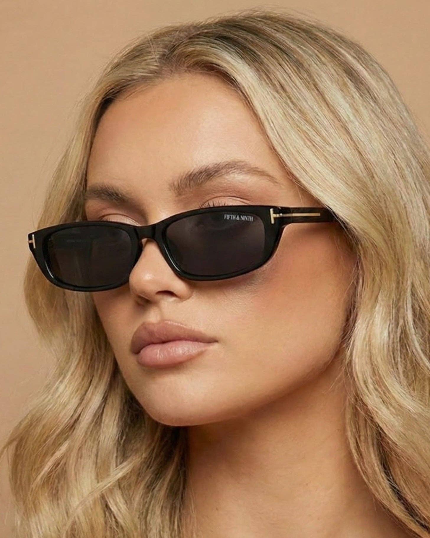 Woman wearing black sunglasses with a neutral background