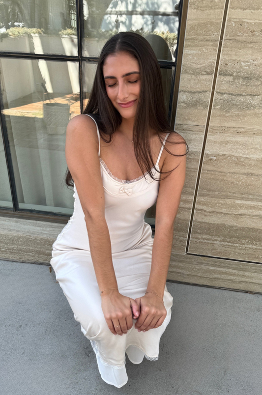 Woman in a white dress sitting on the ground with a modern building in the background