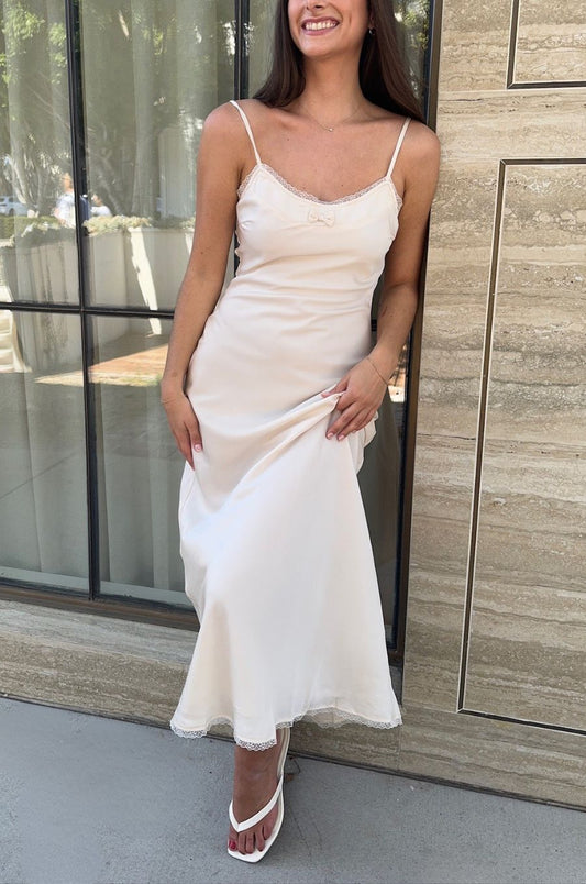 Woman in a white dress standing outdoors next to a building.