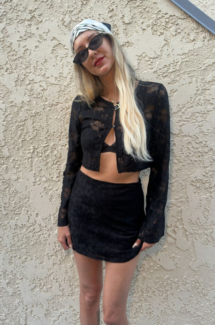 Person wearing a black lace outfit against a textured wall